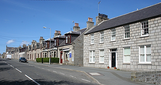 small, rather bleak-looking Victorian housing made of whitish-grey stone, stretching along a roadside