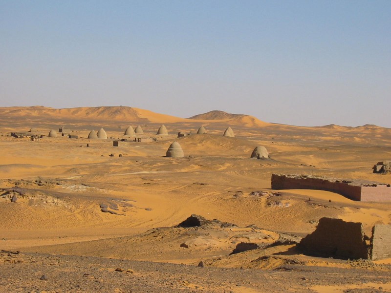 sandy orange landscape dotted with stone structures resembling giant beehives