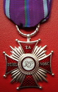 silver medal in the shape of a cross pattée with concave arms, similar in shape to an Iron Cross, with little balls on the eight points of the cross, a roundel bearing the letters RP at the centre and rays coming out from the centre in between the arms, the arms of the cross enamelled in dark red, the ribbon being royal purple with a thin pale-blue stripe up either edge, and up the centre a double thin stripe which is green on the viewer\'s left and rich blue on the right
