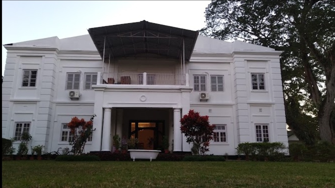 large, white 1920s-ish two-storey building with a square entrance recessed between pillars with a covered balcony above
