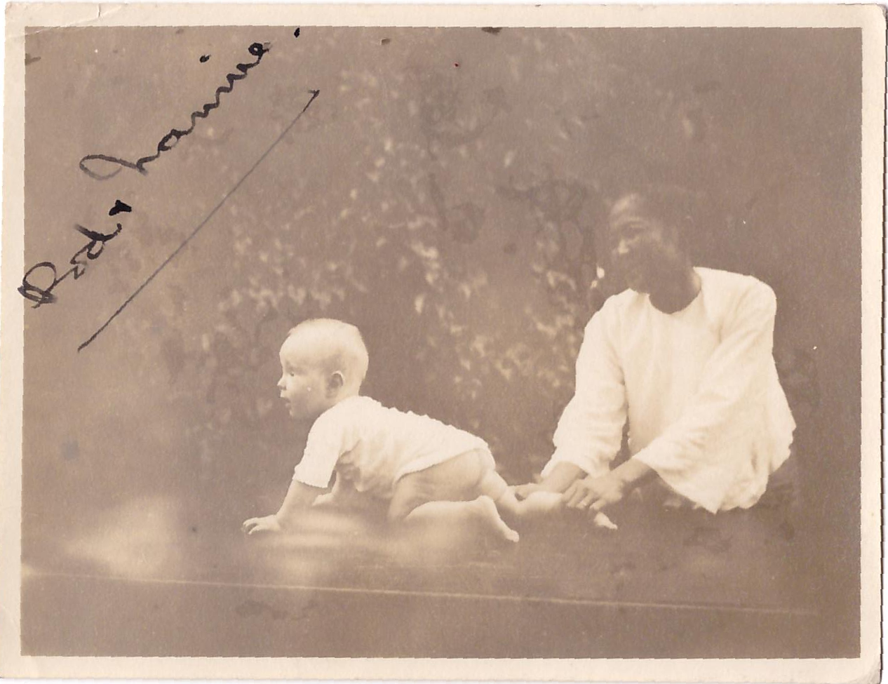 baby Rory crawling, his right leg held by an Asian lady