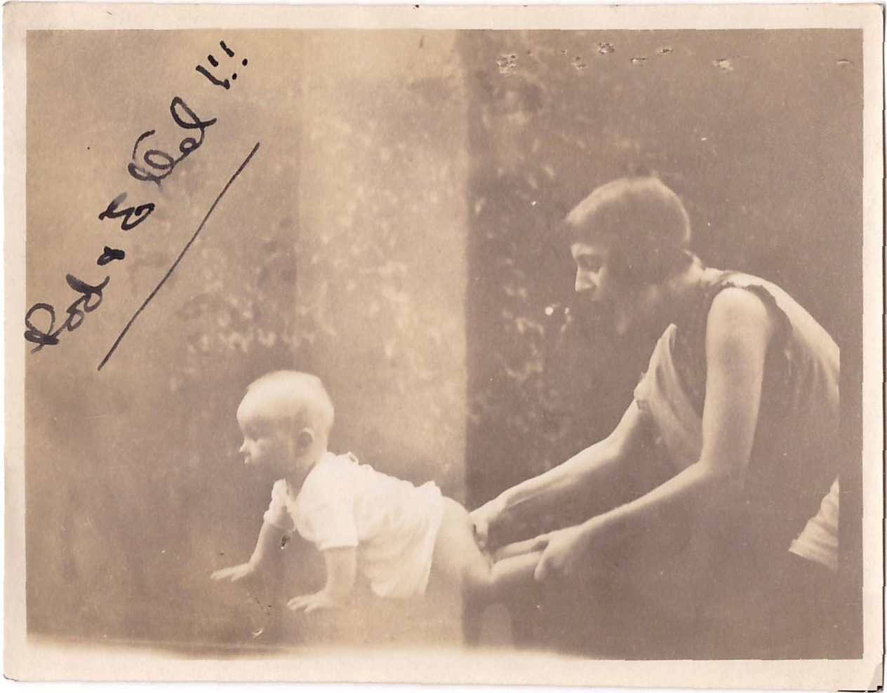 baby Rory crawling, his legs held by Ethel